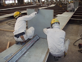 板を持った作業員2人の後ろ姿